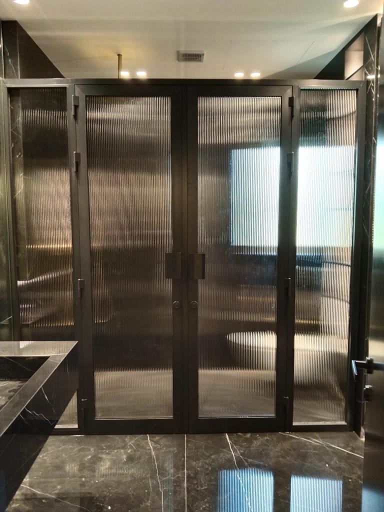 Black-framed fluted reeded glass double doors in a marble interior