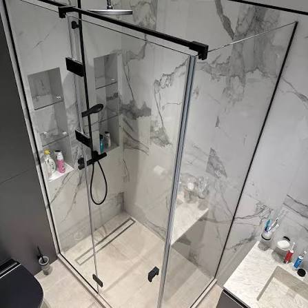 Black framed sliding shower glass enclosure in a marble bathroom