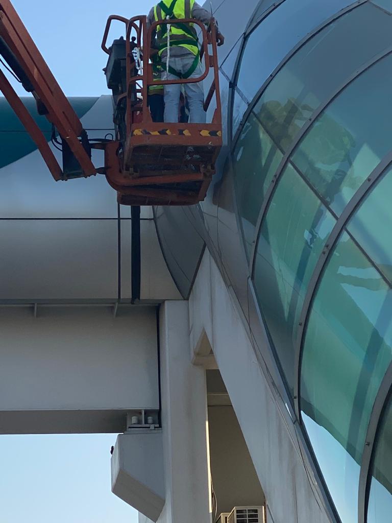 Technician working from a boom lift basket on a curved glass facade