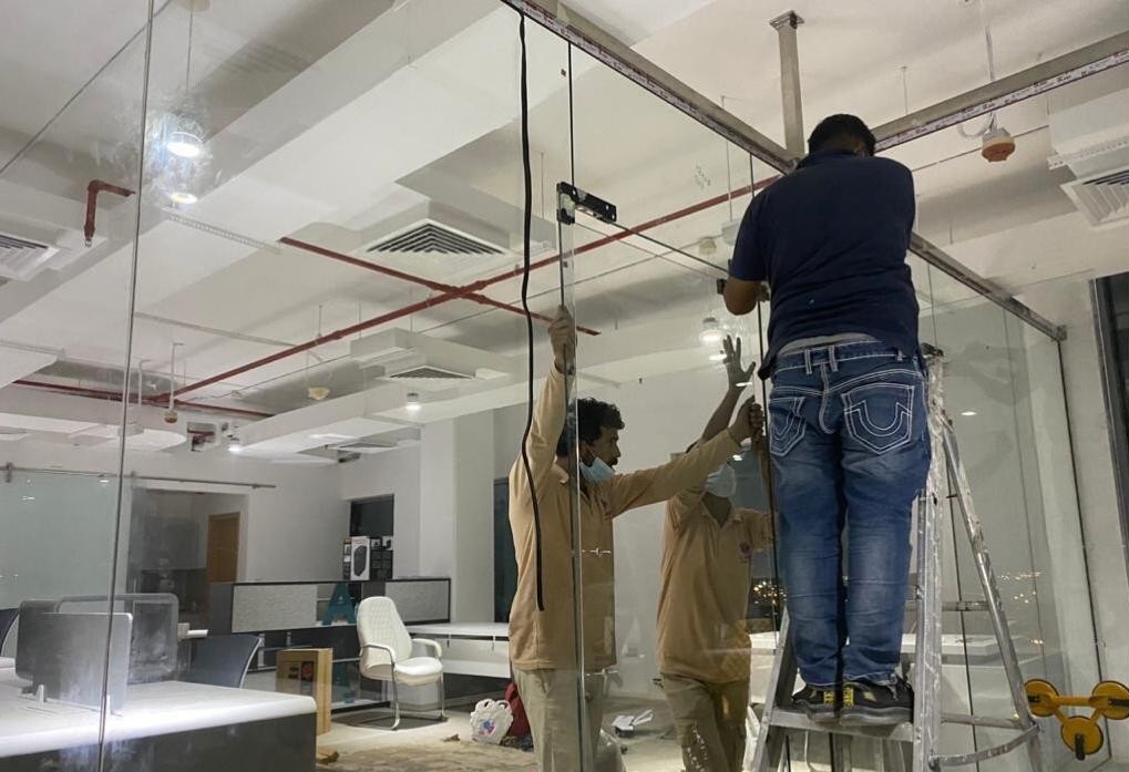 Night-shift glass partition installation inside a working Dubai office