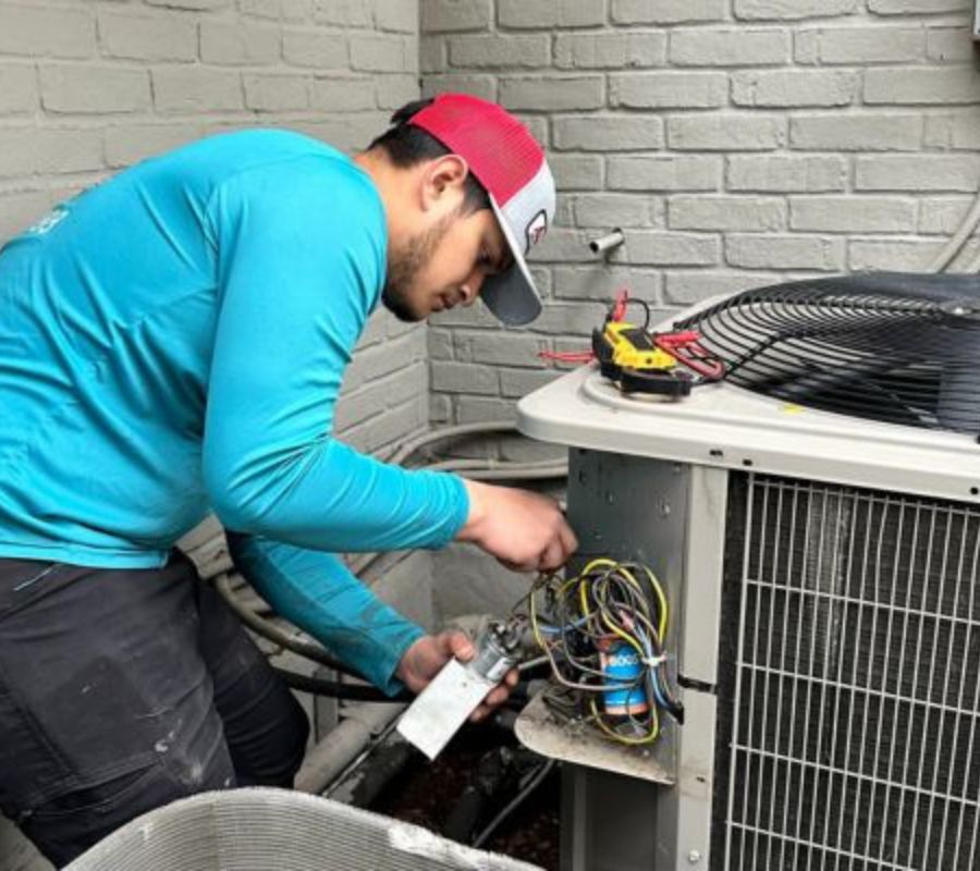 Technician fixing the capacitor and wiring of an outdoor AC condenser unit