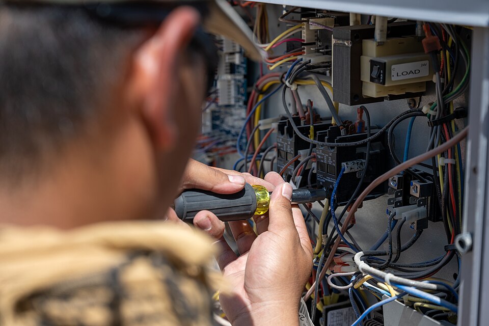 Technician repairing an air conditioner control and wiring panel
