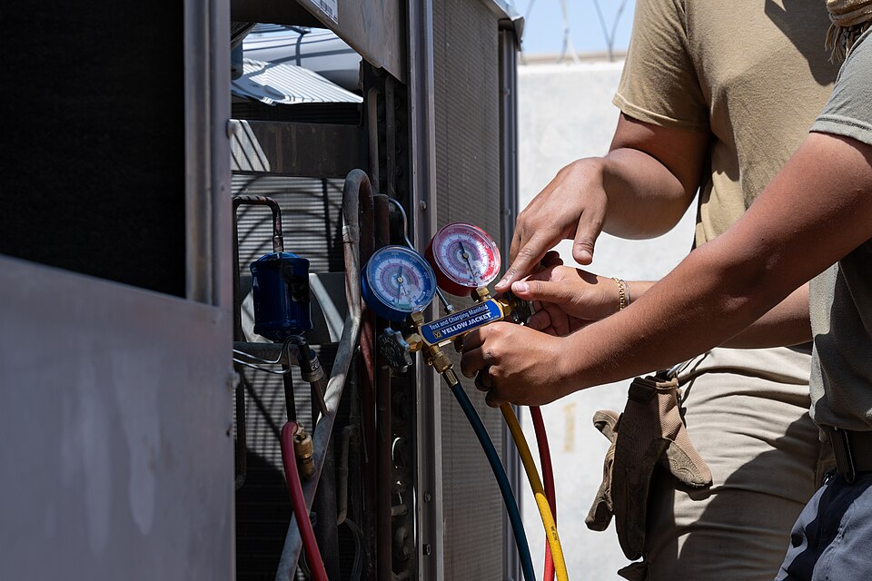 Technician servicing an air conditioner with refrigerant gauges